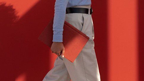 A woman walks with Surface Pro 7 with a Poppy Red Type Cover