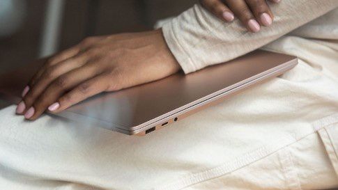 A woman has a closed Surface Laptop 3 on her lap