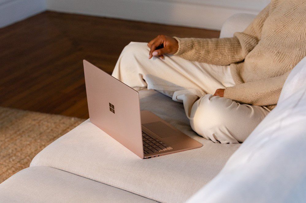 A woman sits in front of Surface Laptop 3 on a couch