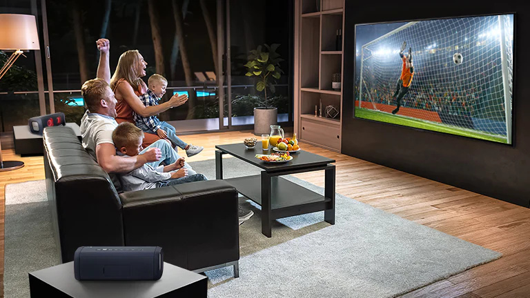 O familie pe canapea uitându-se la un meci de fotbal.