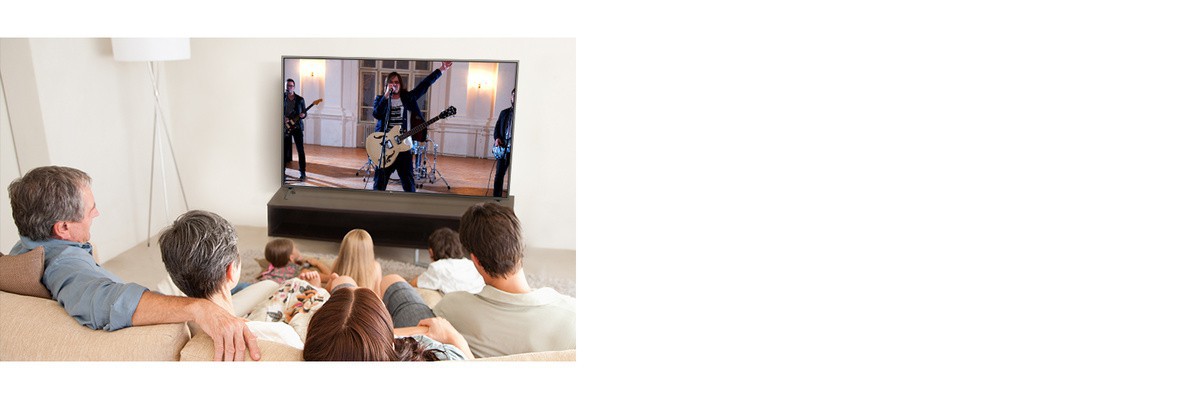 O familie cu sapte membri stau în camera de zi si se uită la un film. Pe ecranul TV apare o formatie care cântă.
