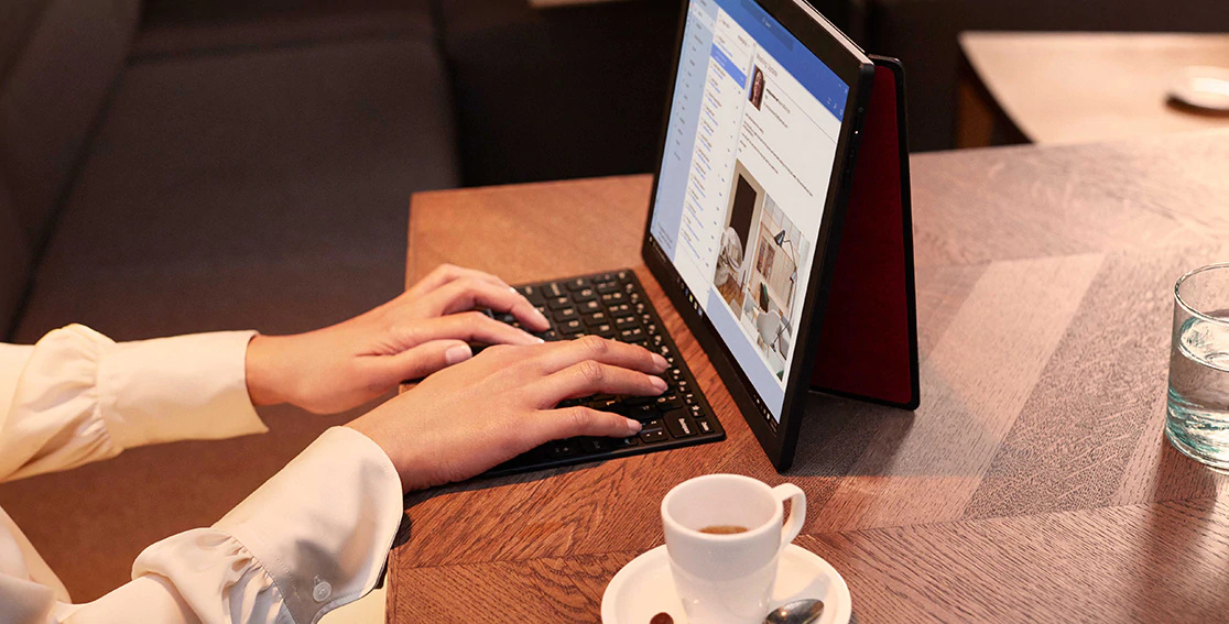 Woman's hands typing on a wireless keyboard, answering email on Lenovo ThinkPad X1 Fold open full screen with back cover stand.