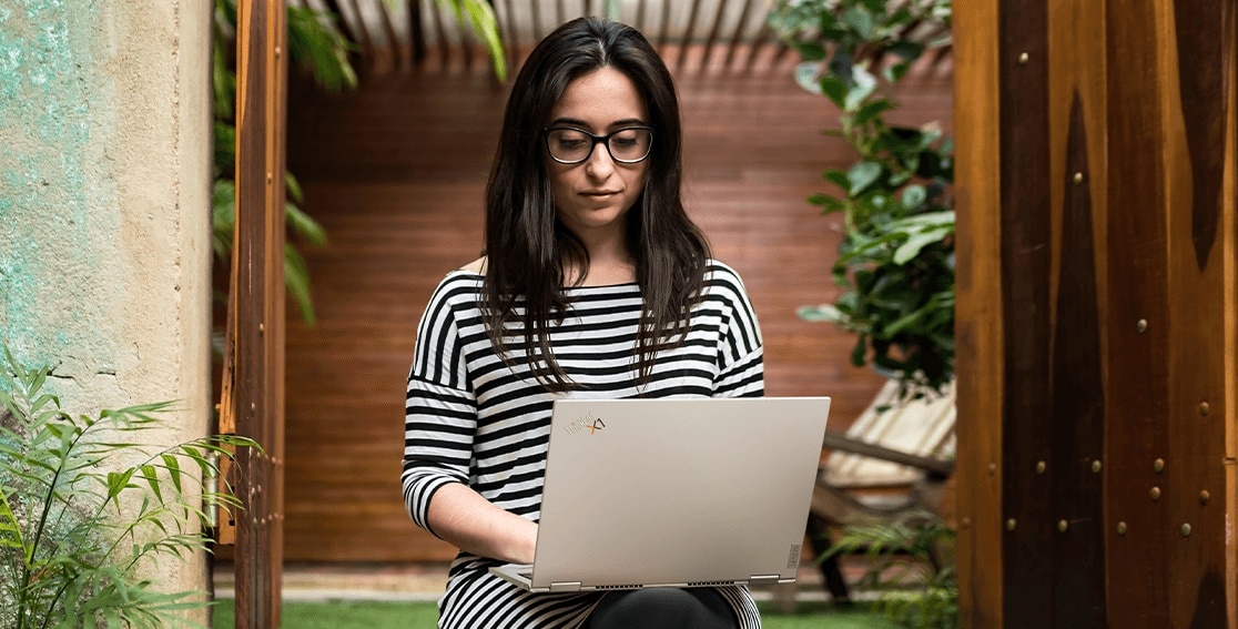 Rearview of Lenovo ThinkPad Titanium Yoga laptop in use on a woman’s lap, open more than 90 degrees.